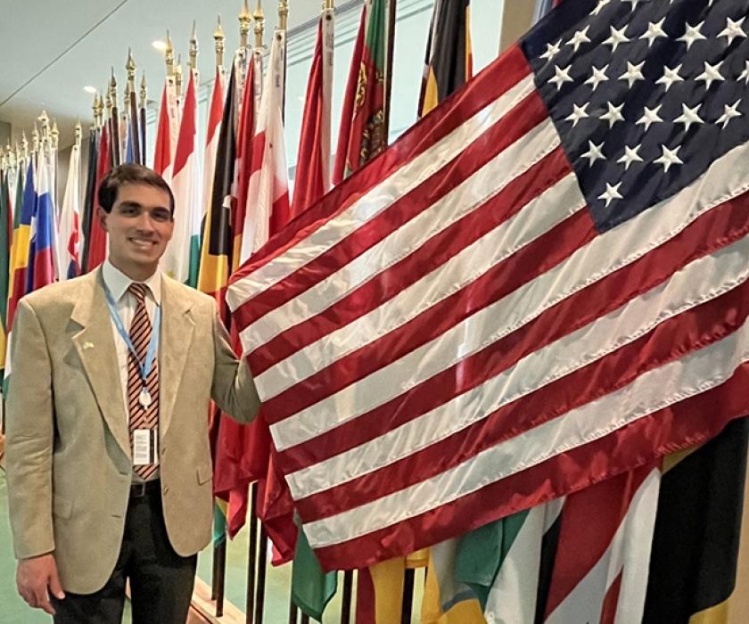 Peter Paolo posing with an American flag next to a row of other national flags